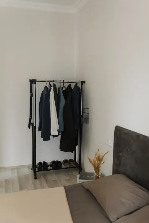 Clothes and shoes arranged on an open rack in a bedroom.